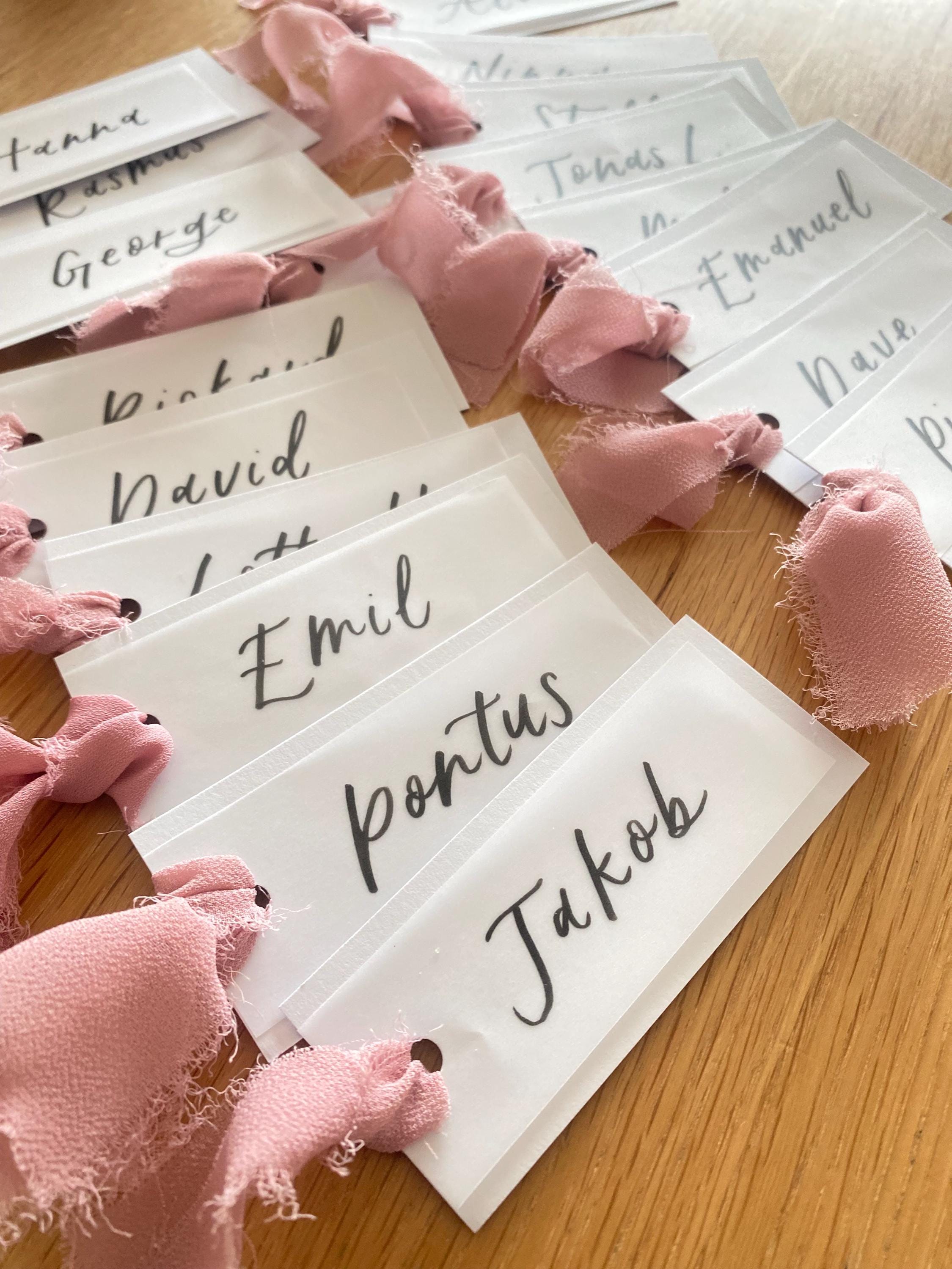 Name tags with pink ribbons on a wooden surface