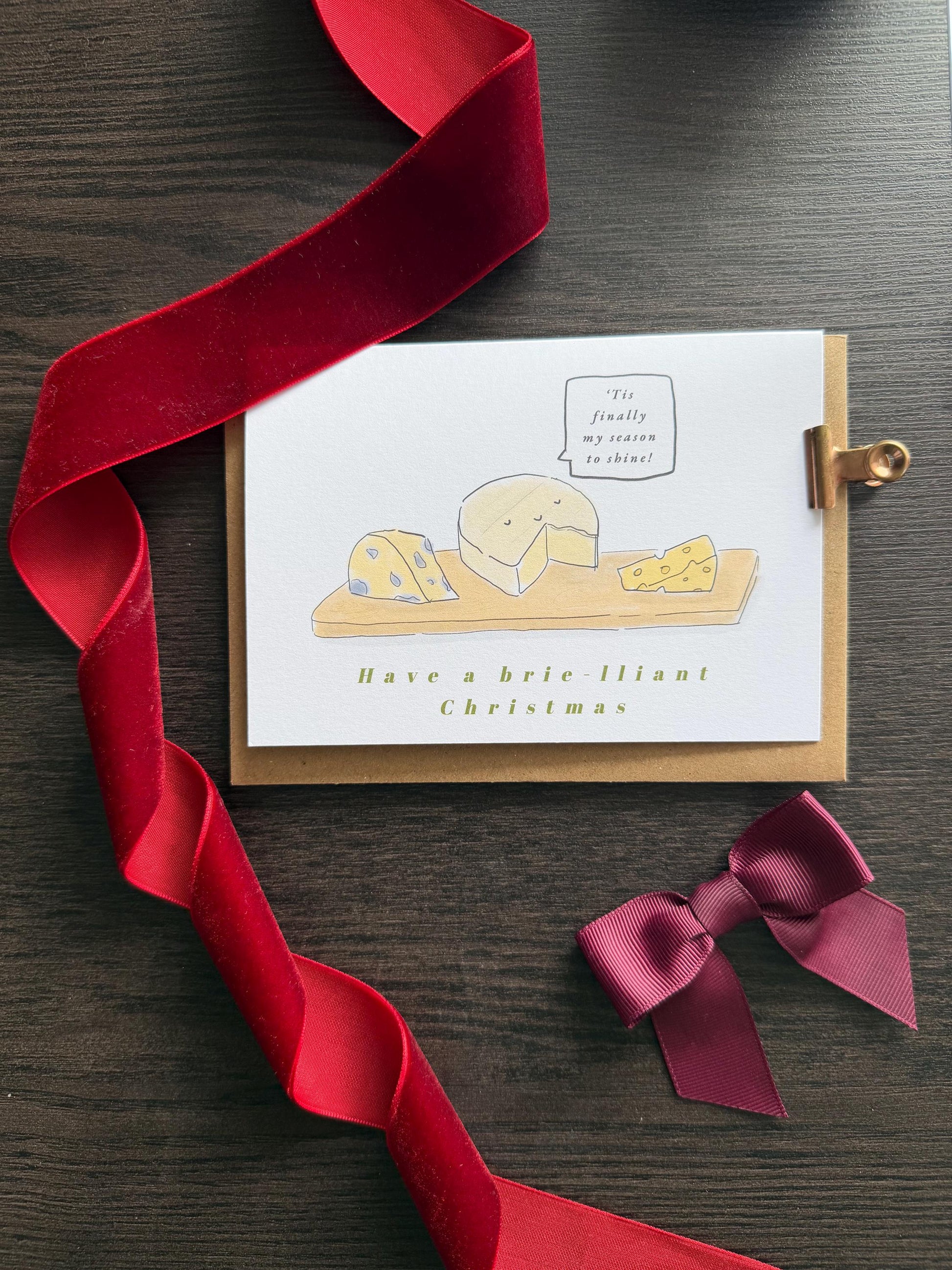 Card with illustration of cheese and red ribbon on wooden surface