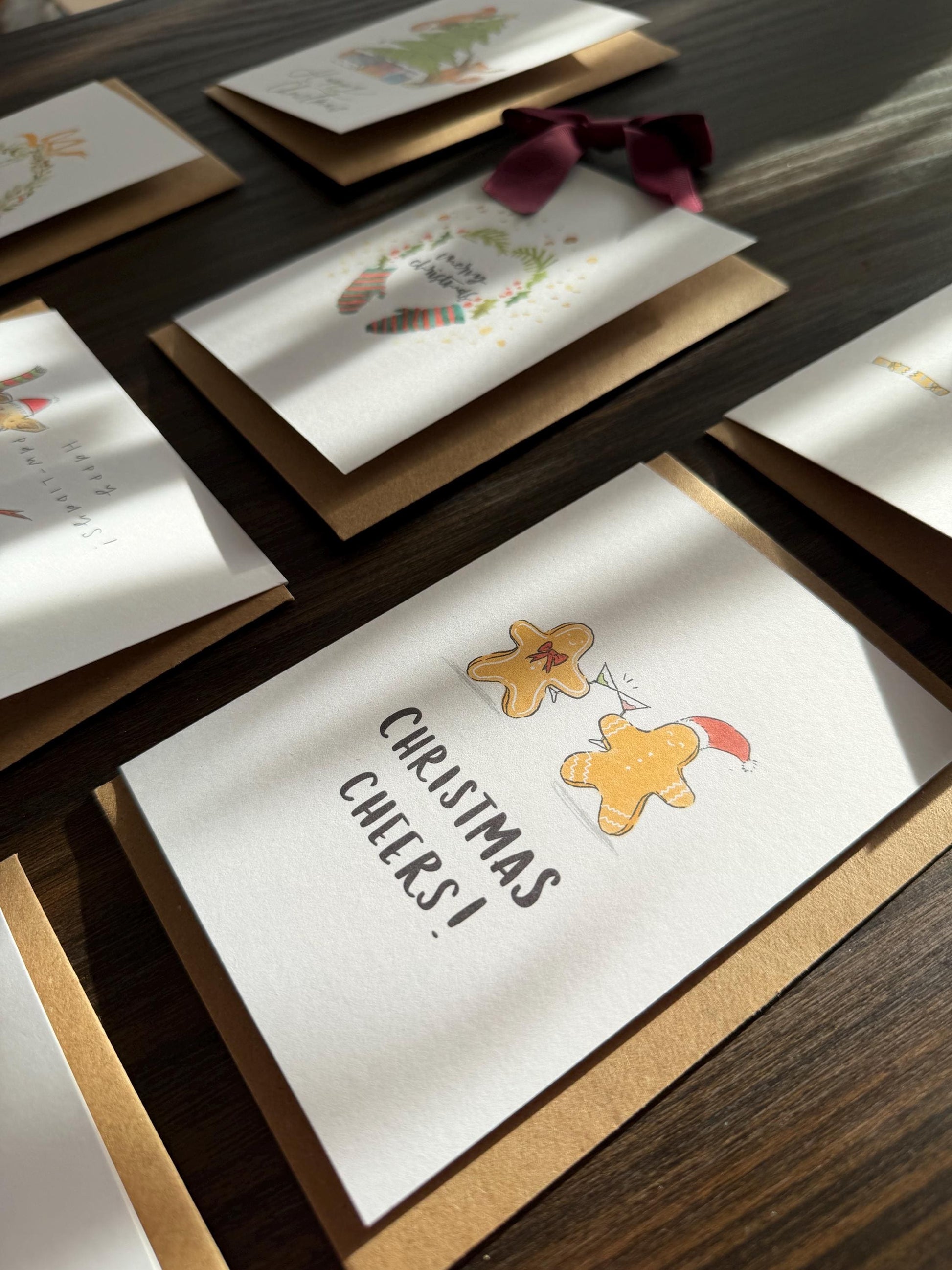Set of Christmas-themed greeting cards with gingerbread men and 'Christmas Cheers!' text on a wooden surface.