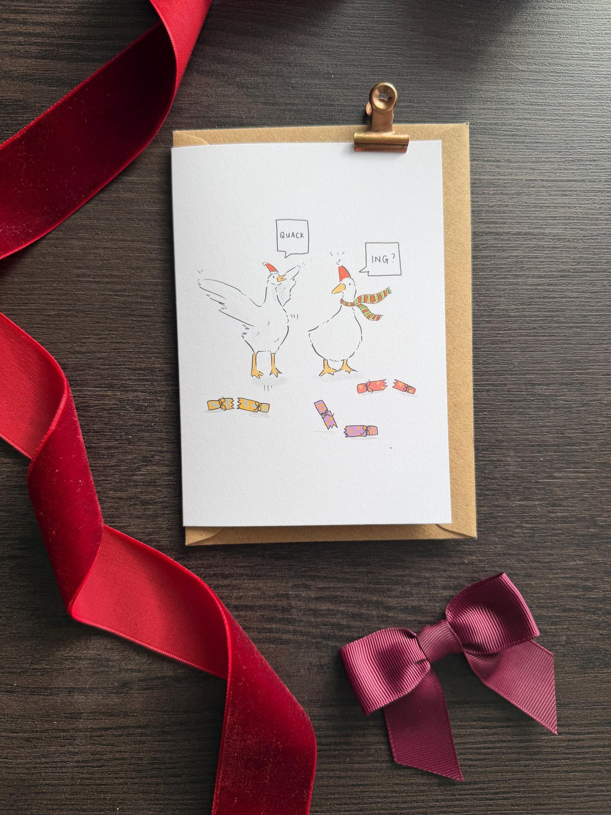 Greeting card with cartoon geese and ribbons on a wooden surface