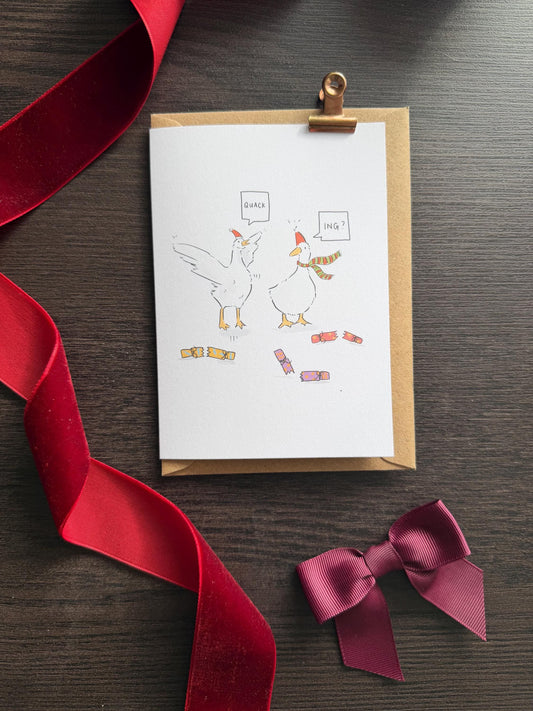 Greeting card with cartoon geese and ribbons on a wooden surface