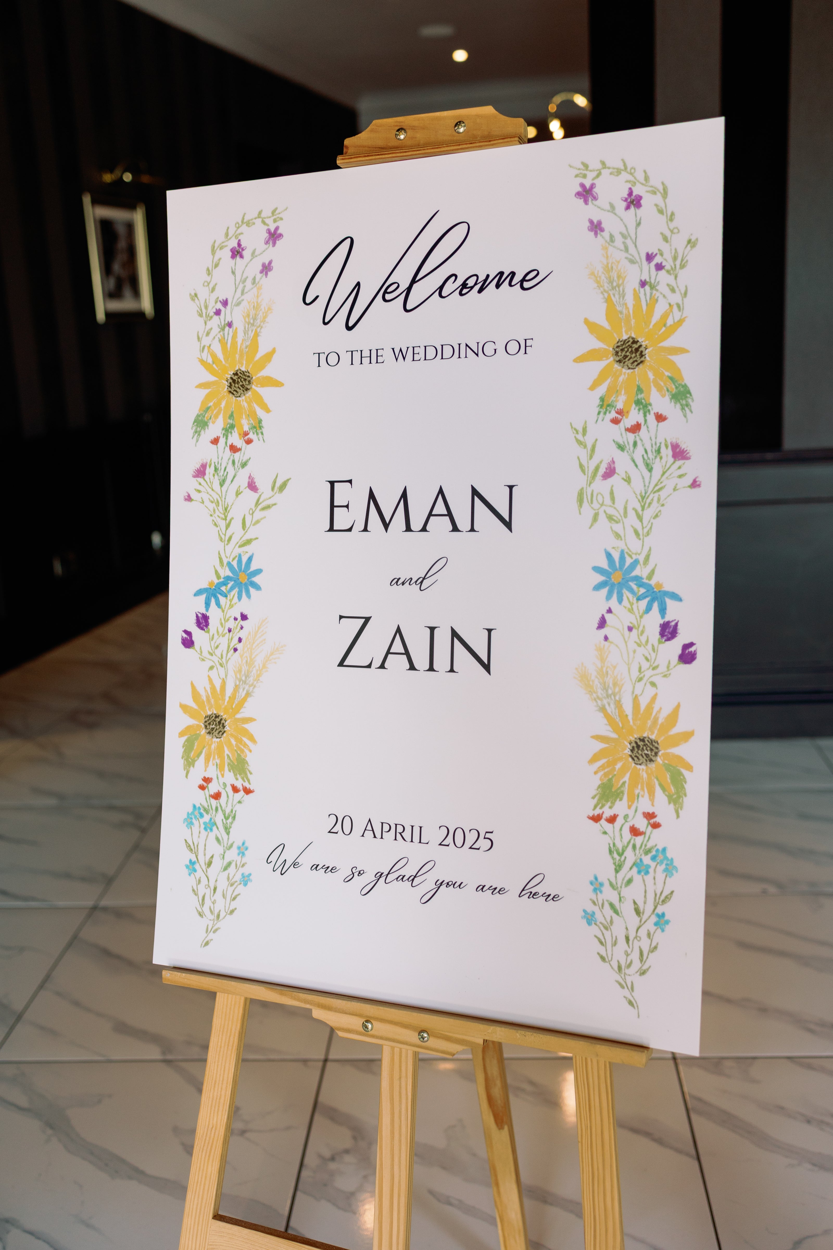 Wedding welcome sign with floral design on a wooden easel.