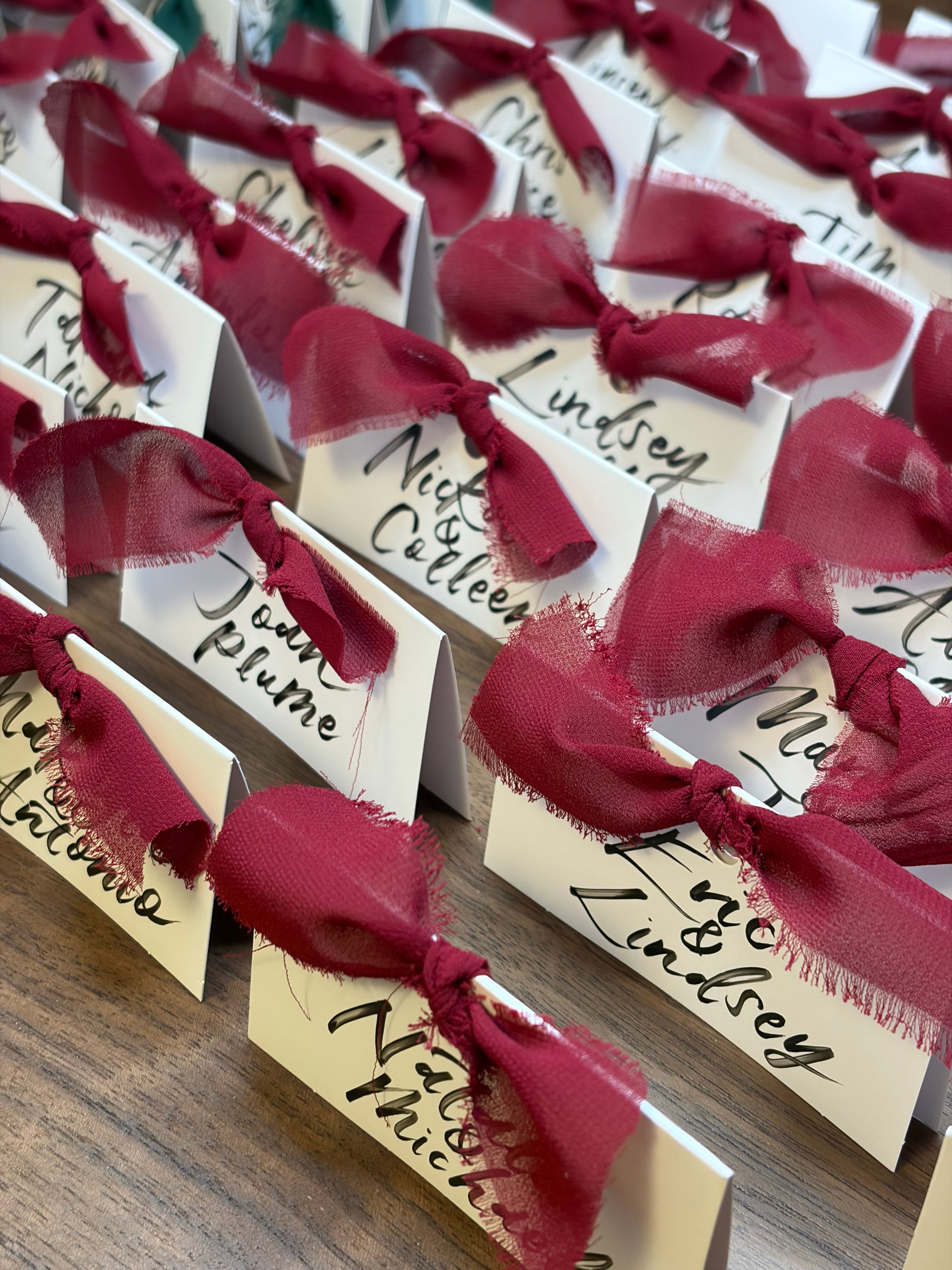 Name cards with red ribbons on a wooden surface