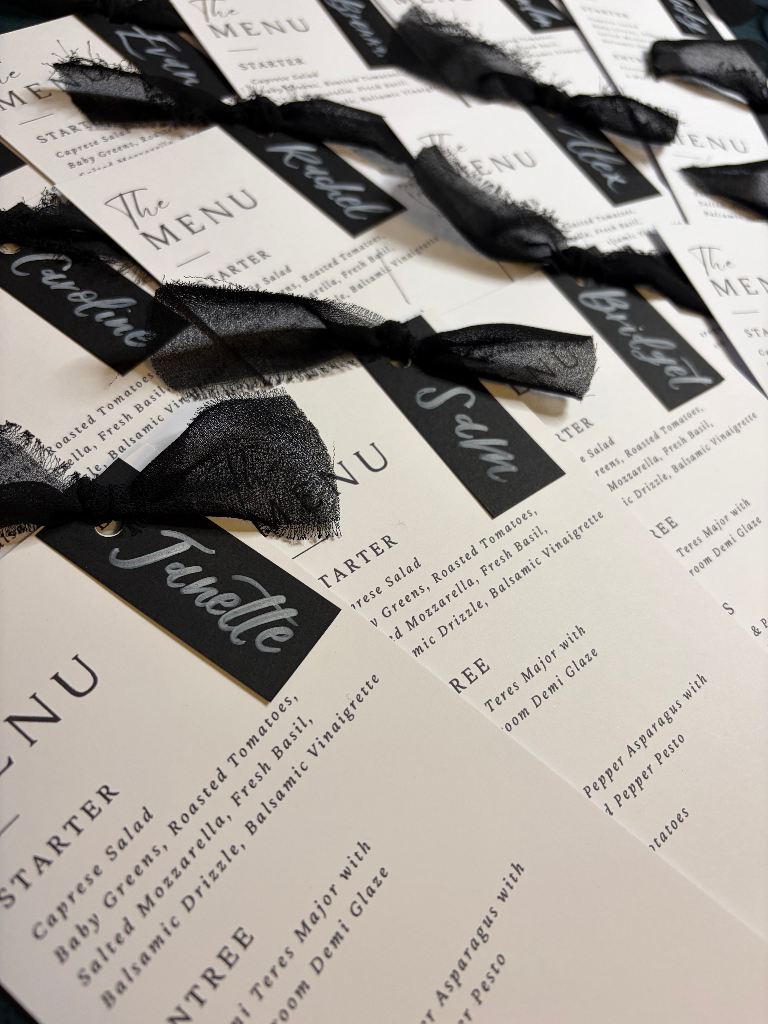 Black ribbons tied to name cards on a textured surface