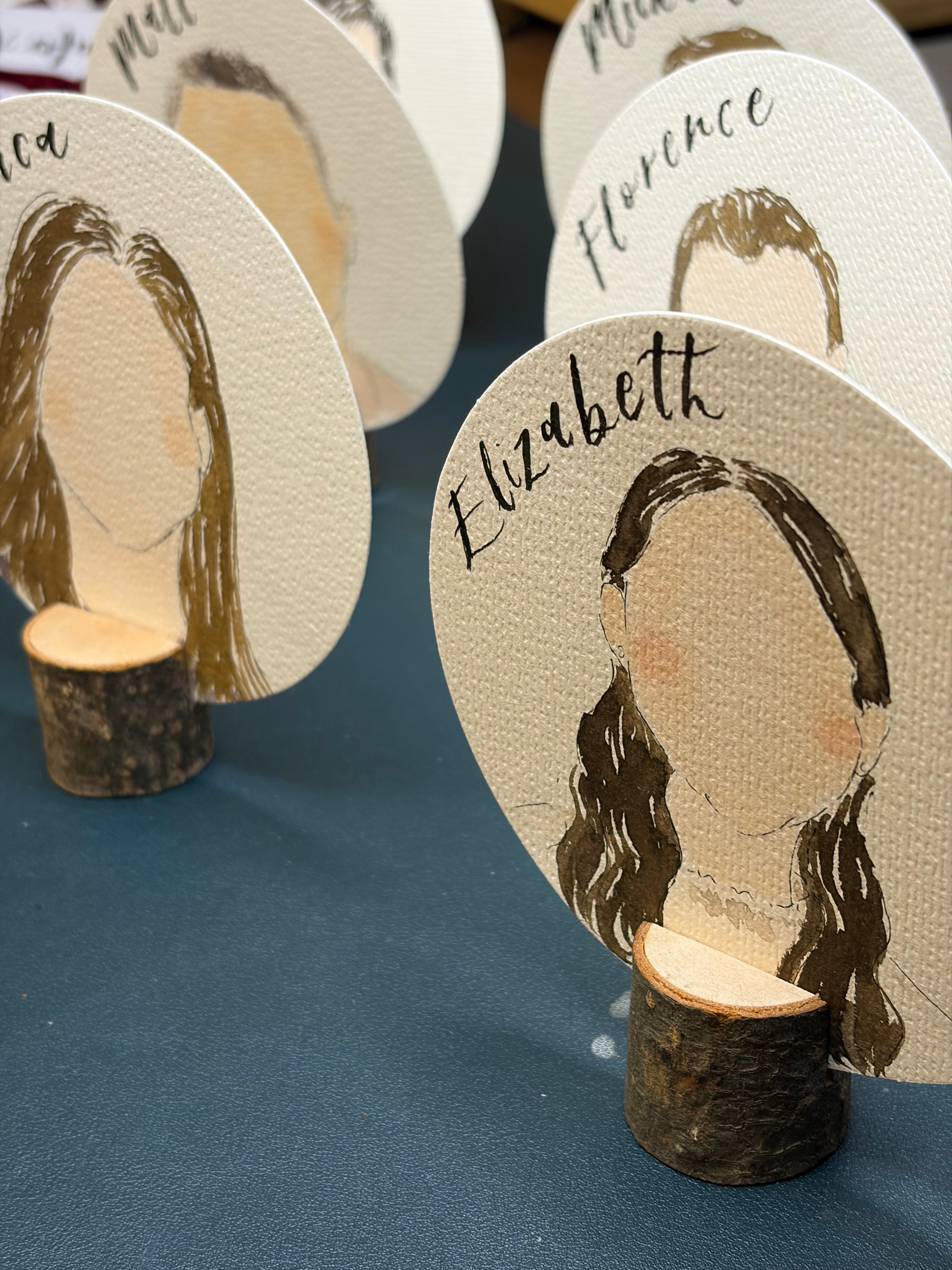 Wooden coasters with engraved faces and names on a blue surface
