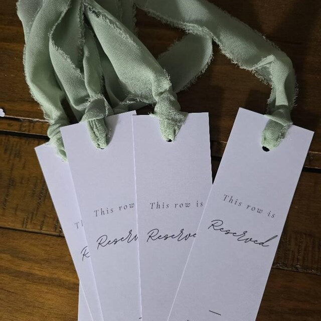 Reserved seat tags on a wooden surface with green fabric draped over them.